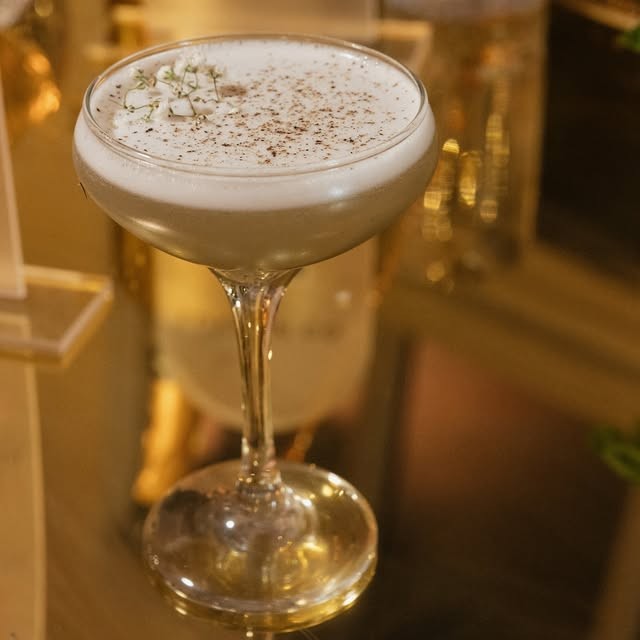 An espresso martini with a dusted foam top in a coupe
